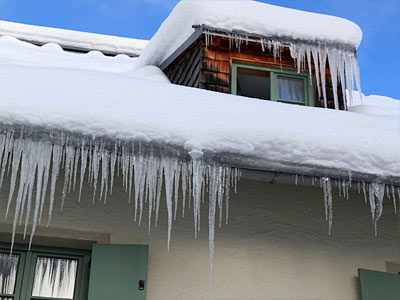 Ein schneebedecktes Dach mit Eiszapfen und einem Fenster.